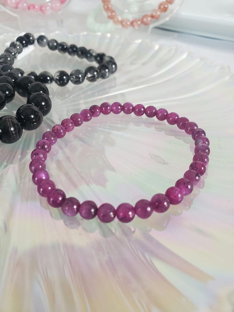 May include: A pink gemstone bracelet with small, round beads. The bracelet is made of natural stones and is a beautiful shade of pink.