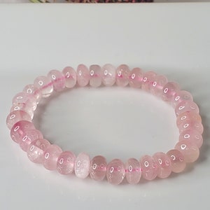 May include: A pink rose quartz beaded bracelet with a stretchy elastic band.