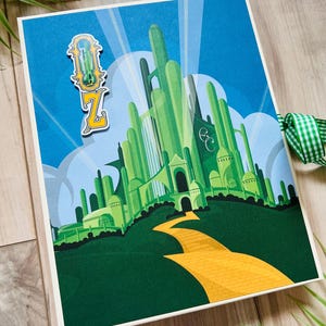 May include: A rectangular card featuring a green illustration of a tall castle with spires, a yellow brick road leading to the entrance, and a blue sky. A decorative emblem with the letter Z and a green hourglass icon is attached to the top left.