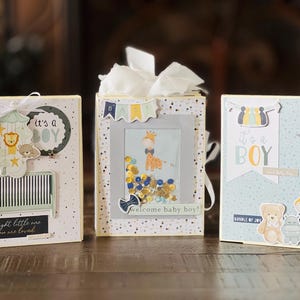 May include: Three baby shower cards with blue, yellow, and white designs. The cards feature a crib, a baby animal mobile, a baby animal, and the text "It's a Boy".