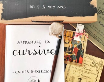 May include: A black and white cursive writing workbook with the title "Apprendre la cursive" and the text "Cahier d'exercice". The workbook is on a wooden table with a pen, inkwell, and vintage postcards.