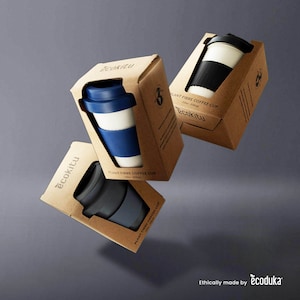 May include: Three cardboard boxes containing plant fibre coffee cups. The boxes are brown with white text that reads "ecokitu" and "PLANT FIBRE COFFEE CUP". The cups are white with blue, black, and grey bands. The text "Ethically made by ecoduka" is at the bottom of the image.