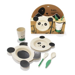 May include: A panda-themed children's tableware set. The set includes a plate, bowl, cup, spoon, and fork. The items are off-white with black and green accents. The packaging features a panda face and the text "ecokitu Children's Tableware Set Panda".