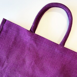 May include: A purple tote bag made of woven fabric with thick purple fabric handles.