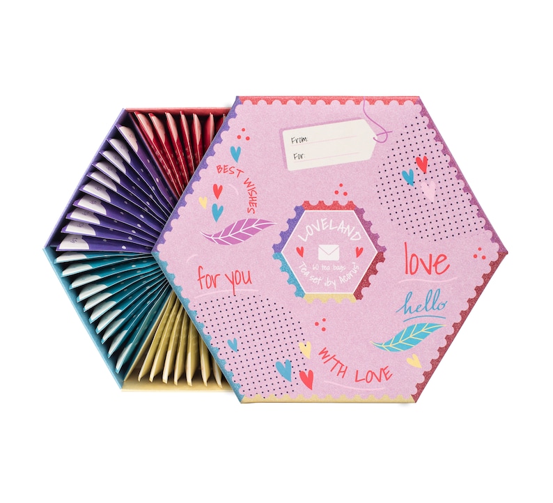 K&ouml;nnte beinhalten: Eine sechseckige Box mit einem rosa-wei&szlig;en Design mit Herzen, einer Feder und den Worten "Beste W&uuml;nsche", "f&uuml;r dich", "Loveland", "Liebe", "Hallo" und "Mit Liebe". Die Box ist ge&ouml;ffnet und zeigt einen F&auml;cher mit bunten Teebeuteln.