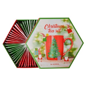 May include: A hexagonal box with a red and green Christmas tea set. The box features a red mug with a Christmas tree design and the text "Christmas tea set" and "By ACORUS".