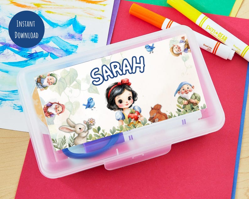 Pu&ograve; includere: Un astuccio trasparente in plastica con un'illustrazione colorata di Biancaneve e il nome "Sarah". L'illustrazione include Biancaneve, nani, un coniglio e un uccellino blu. L'astuccio &egrave; su una superficie rossa con pennarelli.