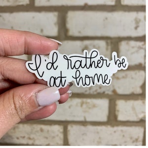May include: White sticker with black cursive text that reads "I'd rather be at home".