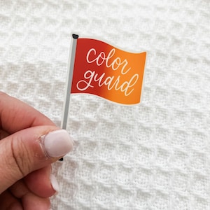 May include: A red and orange flag with the text "color guard" written in white cursive.
