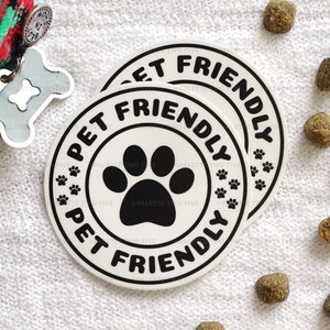 May include: Two white round stickers with black text and a paw print. The text on the stickers reads "Pet Friendly".