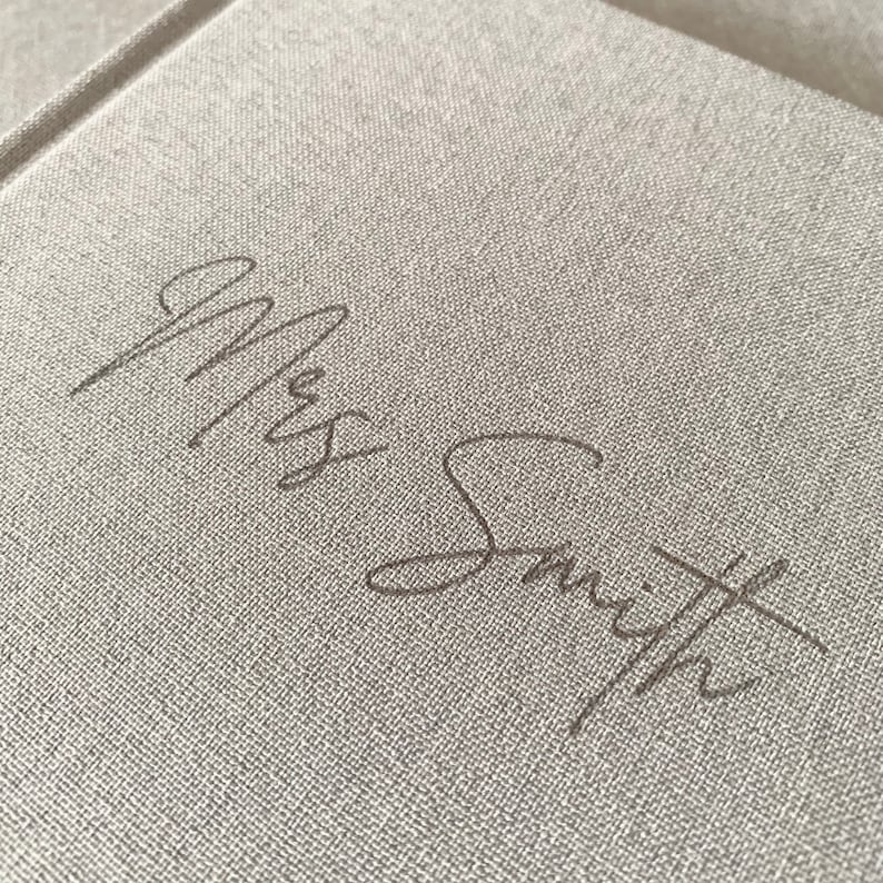 May include: A close-up of a light gray fabric journal with the name "Mrs. Smith" written in cursive on the front cover.