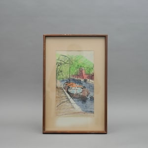 May include: A framed watercolor painting depicting a canal scene with a boat docked on the water. The painting features a green tree canopy, red brick buildings, and a blue sky.
