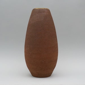 May include: A brown ceramic vase with a textured surface. The vase is tall and narrow, with a rounded bottom and a slightly flared opening.