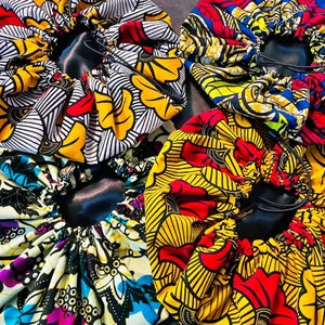 May include: Four colorful satin fabric hair bonnets with elastic bands and drawstrings. The bonnets are in various patterns of yellow, red, blue, and black.