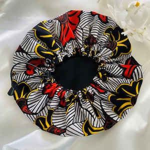 May include: A black, white, red, and yellow patterned satin sleep cap with a drawstring closure.