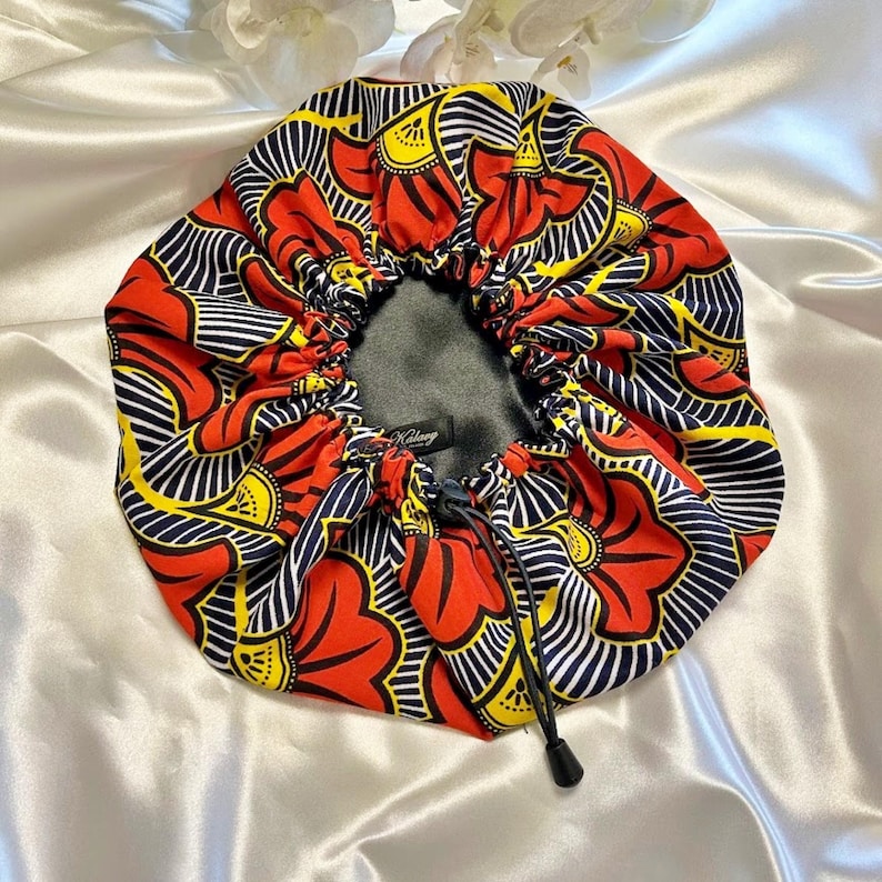 May include: Red, yellow, and blue patterned satin bonnet with a black drawstring.