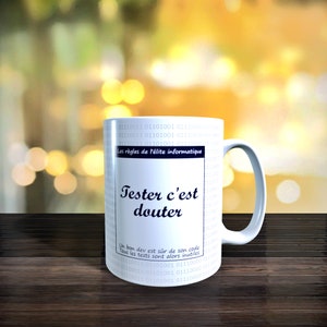 Peut inclure: Une tasse en céramique blanche avec un motif de code binaire noir et blanc. La tasse porte une inscription bleue qui dit "Tester c'est douter" et "Un bon dev est sur de son code. Tous les tests sont alors inutiles."