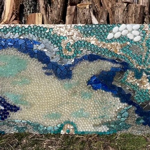 May include: A mosaic artwork depicting a blue and white bird in flight, with a background of green and white glass pieces.