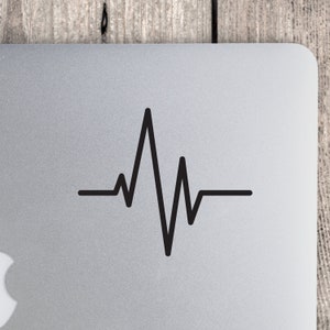 May include: A black and white heartbeat graphic sticker on a silver laptop.