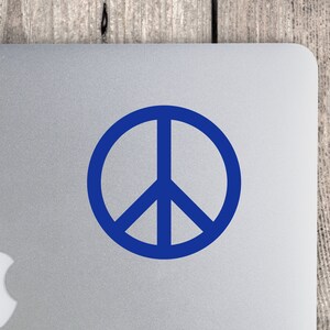 May include: A blue peace sign sticker on a silver laptop.
