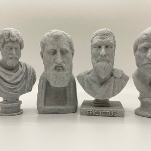 Puede incluir: Cuatro bustos de piedra gris de figuras hist&oacute;ricas, cada uno con una expresi&oacute;n facial y un peinado &uacute;nicos. El busto del centro tiene el nombre "Epicteto" inscrito en la base.