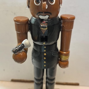 Puede incluir: Una taza de cerámica blanca con un asa negra y el texto "But First, Coffee" en negro y negrita. La taza está sobre una superficie de madera. La taza mide aproximadamente 10 cm de alto.