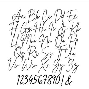 May include: A black and white image displaying a complete cursive alphabet, including uppercase and lowercase letters, along with numbers 0-9, an exclamation point, and an ampersand. The elegant, handwritten style is perfect for design projects.