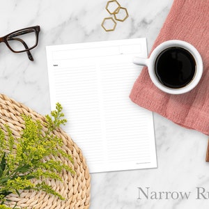 May include: A blank printable page with narrow ruled lines, divided into two columns. The page is on a white marble surface with a coffee cup, a wooden spoon, a woven placemat, and a pair of glasses.