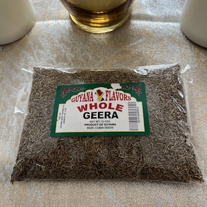 May include: A clear plastic bag filled with brown cumin seeds. The bag has a green label that reads "GUYANA FLAVORS WHOLE GEERA NET WT. 12 OZS. PRODUCT OF GUYANA INGR: CUMIN SEEDS".