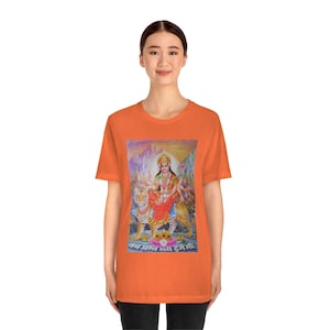 May include: Orange t-shirt with a colorful image of a Hindu goddess riding two tigers. The image is surrounded by a mountain range and the text "जय जय दुर्गा माँ" is printed below the image.