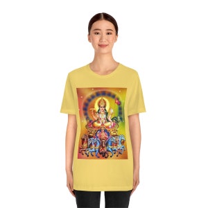 May include: A yellow t-shirt with a colorful image of the Hindu deity Surya, the Sun God, riding a chariot pulled by seven horses. The image is surrounded by a halo of light and stars.