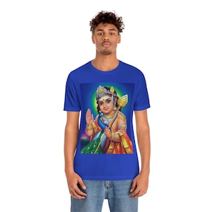 May include: A royal blue t-shirt with a colorful image of a Hindu deity, Murugan, holding a peacock feather and a spear. The deity is wearing a gold crown and a yellow and red robe.
