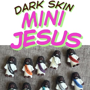 May include: A collection of miniature figurines of Jesus with dark skin, wearing white robes and sashes with the text "Jesus ❤️ You". The text "Dark Skin Mini Jesus" is displayed above the figurines in pink and green.