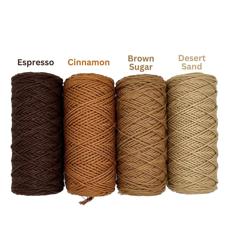 Puede incluir: Cuatro carretes de hilo en tonos marrones variados. Los colores est&aacute;n etiquetados como "Espresso", "Canela", "Az&uacute;car moreno" y "Arena del desierto". El hilo est&aacute; bien enrollado y los carretes est&aacute;n colocados uno al lado del otro sobre un fondo blanco.