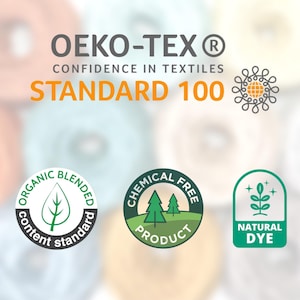 Puede incluir: Imagen con el logotipo OEKO-TEX Standard 100, que indica confianza en los textiles. Insignias adicionales resaltan el contenido org&aacute;nico mezclado, los productos libres de qu&iacute;micos y el tinte natural. El fondo es una suave mezcla borrosa de colores.