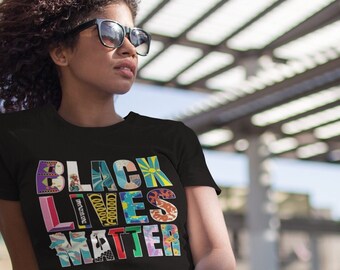 May include: A person wearing a black t-shirt with the words "Black Lives Matter" printed in colorful letters. The letters are made up of different images and patterns.