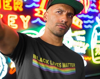 May include: A person wearing a black t-shirt with the text "Black Lives Matter" in yellow letters and a rainbow stripe below the text. The person is wearing a green baseball cap with the text "ST 20" on it.