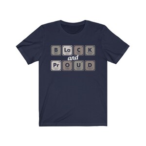 May include: Navy blue t-shirt with the words "Black and Proud" spelled out using periodic table elements. The design features the elements Boron, Lanthanum, Carbon, Potassium, Praseodymium, Oxygen, Uranium, and Deuterium.