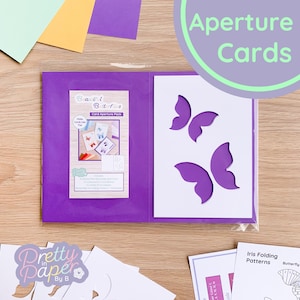 Puede incluir: Un paquete de apertura de tarjetas de color morado con una tarjeta blanca en el interior que presenta un diseño de mariposa. El paquete incluye 5 tarjetas de apertura de mariposa, 5 tarjetas en blanco A5 de colores, 5 sobres blancos A5 y patrones de plegado de iris de mariposa.