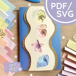 Puede incluir: Una descarga digital de un proyecto de artesanía en papel con una concha, una estrella de mar y olas. El proyecto está hecho con papel de colores y tiene un acento de purpurina dorada. La descarga incluye archivos PDF y SVG.