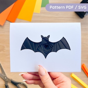 May include: A white rectangular card featuring a die-cut bat silhouette. The interior of the bat shape reveals a layered, spiral-like paper construction in shades of black and dark grey. The text Pattern PDF / SVG is visible in the upper corner.