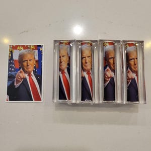 May include: Five clear acrylic blocks with a printed image of a man in a suit and red tie pointing at the viewer. The man's face is visible in each block.