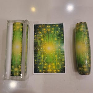 May include: A set of three items with a circuit board design. The set includes a clear acrylic container holding a cylindrical object, a rectangular card, and a rounded, cylindrical object. The design features green and yellow lines and dots.