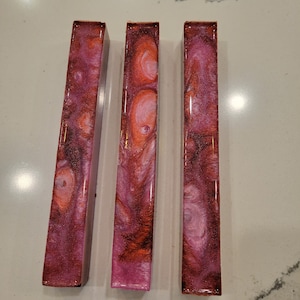 May include: Three long, thin, rectangular resin blanks with a pink, white, and orange marbled pattern.