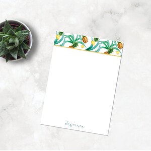 May include: A white notepad with a gold border and a pineapple pattern. The notepad has the name "Jasmine" written at the bottom.