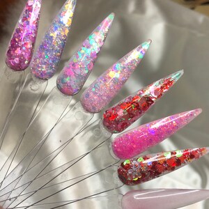 May include: Assortment of six small jars filled with different colors of glitter. The glitter is iridescent and has a variety of shapes, including hearts, stars, and circles.