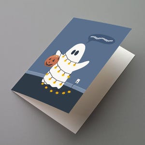 May include: A Halloween-themed greeting card featuring a cartoon ghost wrapped in string lights and carrying a jack-o'-lantern. The ghost has a speech bubble with the sound "booooo". The card is white inside and has a blue background.