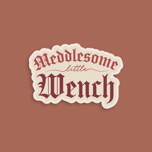 May include: A white sticker with a red, cursive font that reads "Meddlesome little Wench".