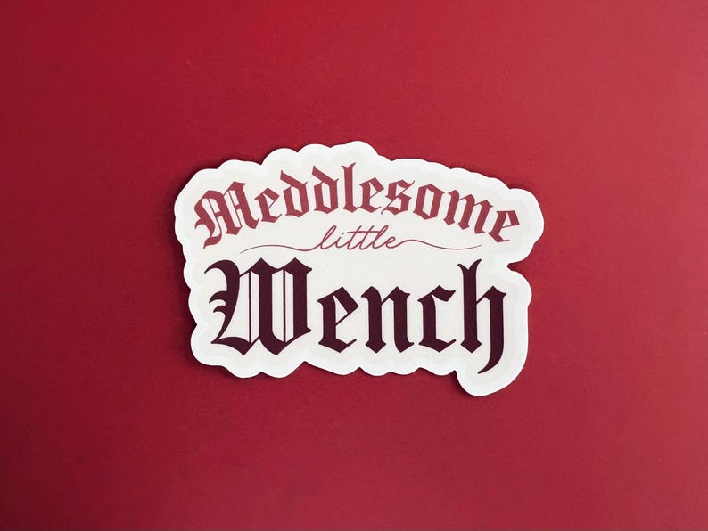Puede incluir: Pegatina blanca con texto negro que dice "Meddlesome little Wench" en una fuente g&oacute;tica.