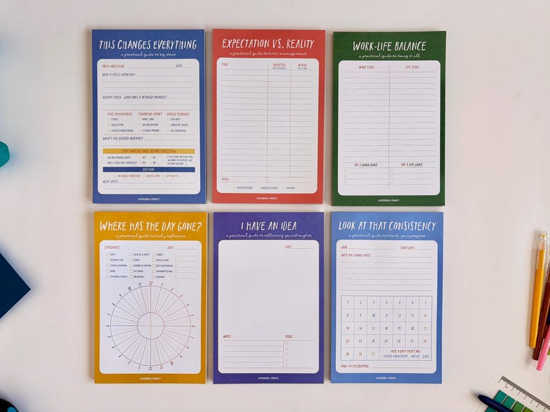 May include: A set of six colorful notepads with various titles and layouts. The titles include "This Changes Everything," "Expectation vs. Reality," and "Work-Life Balance." Each notepad has a different color border and contains lines and prompts for writing.